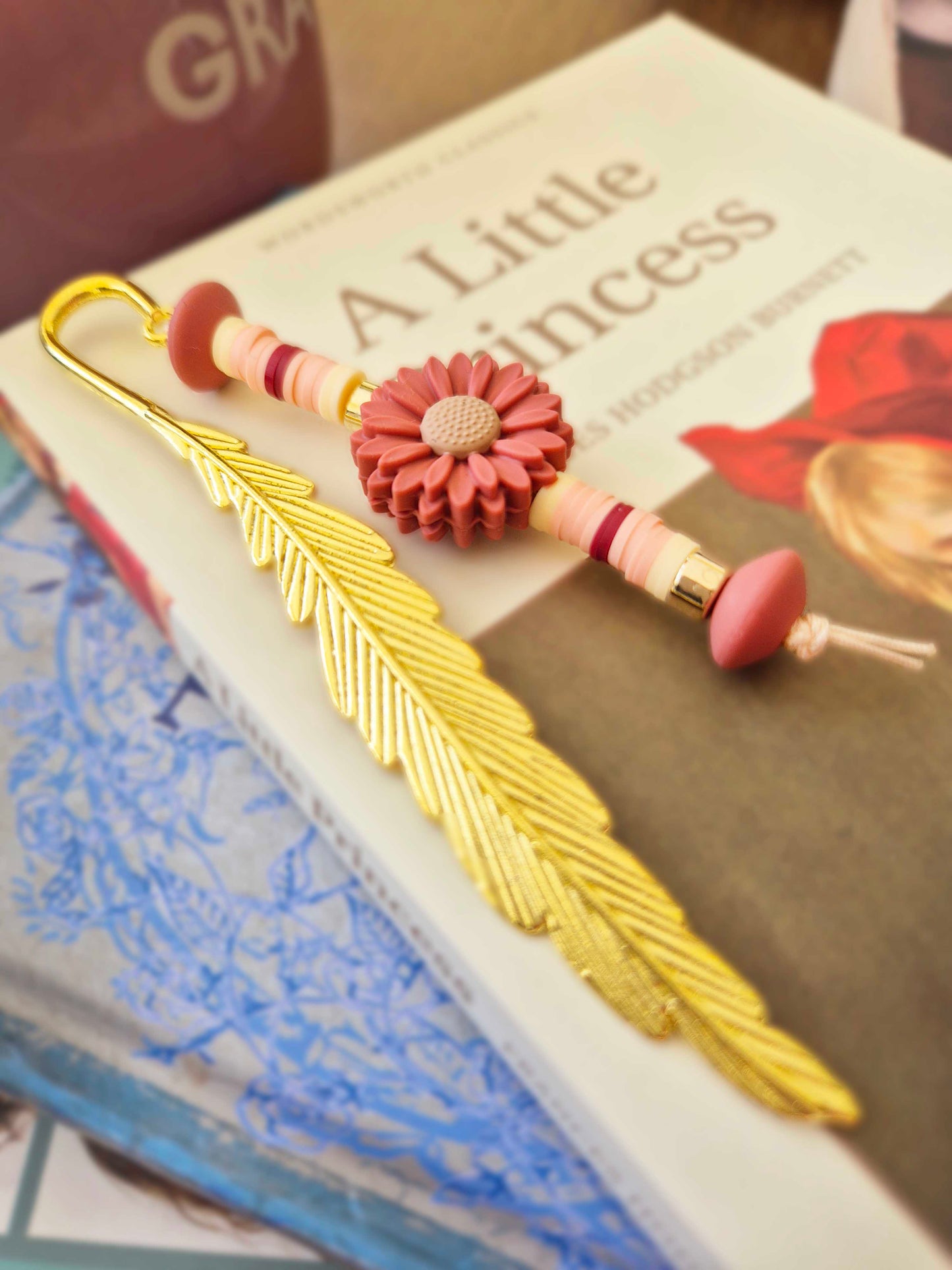 Gold feather bookmark decorated with beads. Floral bead as a central focal bead.