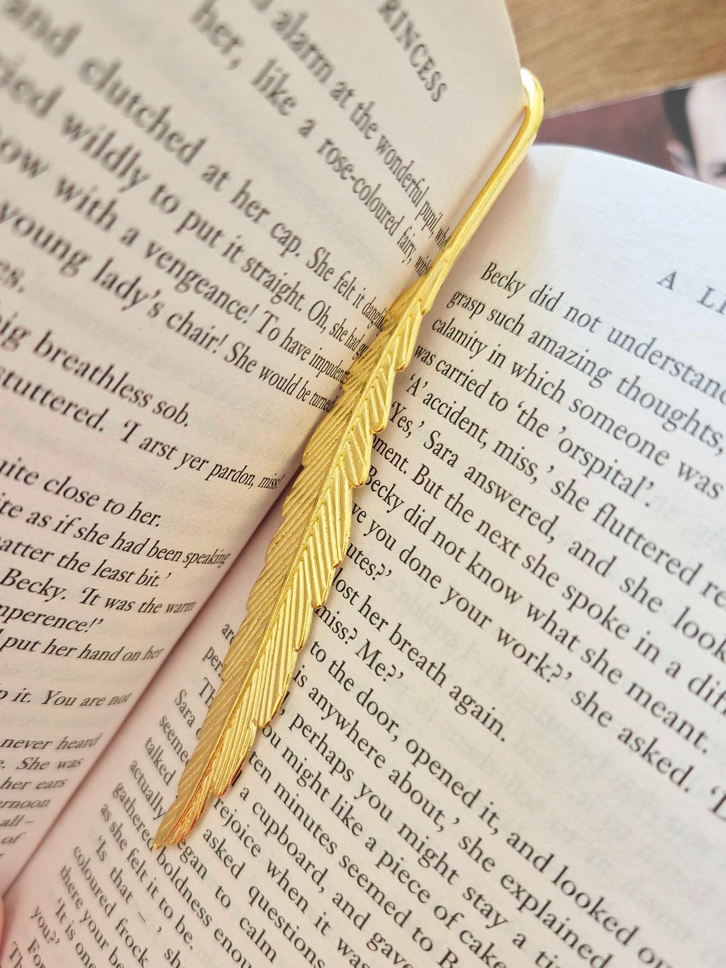 Gold feather bookmark decorated with beads. Floral bead as a central focal bead.