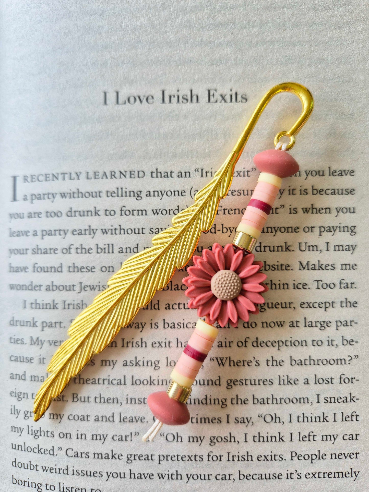 Gold feather bookmark decorated with beads. Floral bead as a central focal bead.