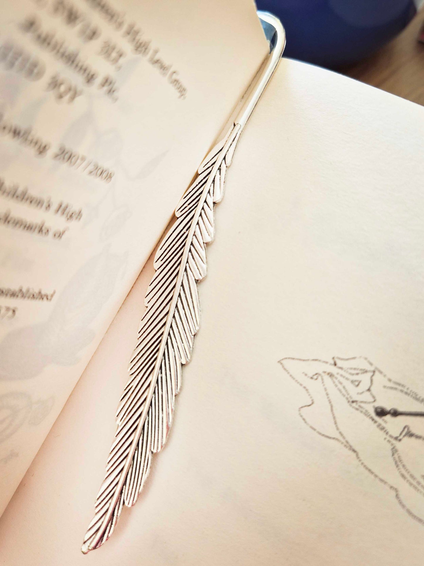 Silver feather bookmark decorated with beads. Stack of books as a focal bead.