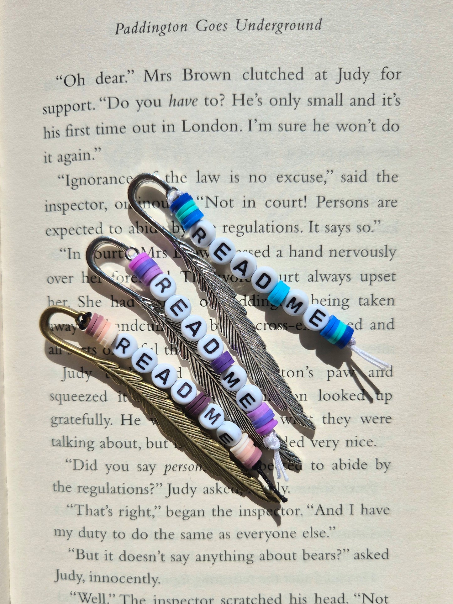 Mini feather bookmarks in silver, bronze and gold. Made with beads saying READ ME