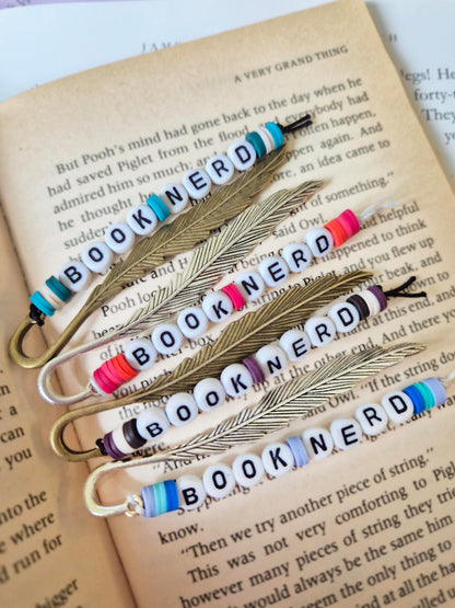 Mini feather bookmarks in silver, bronze and gold. Made with beads saying BOOK NERD