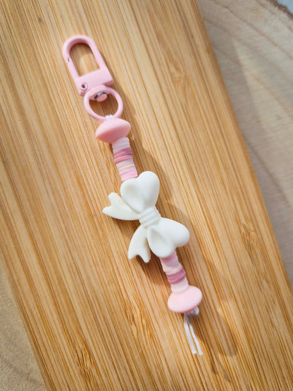 White bow keychain on wooden board.