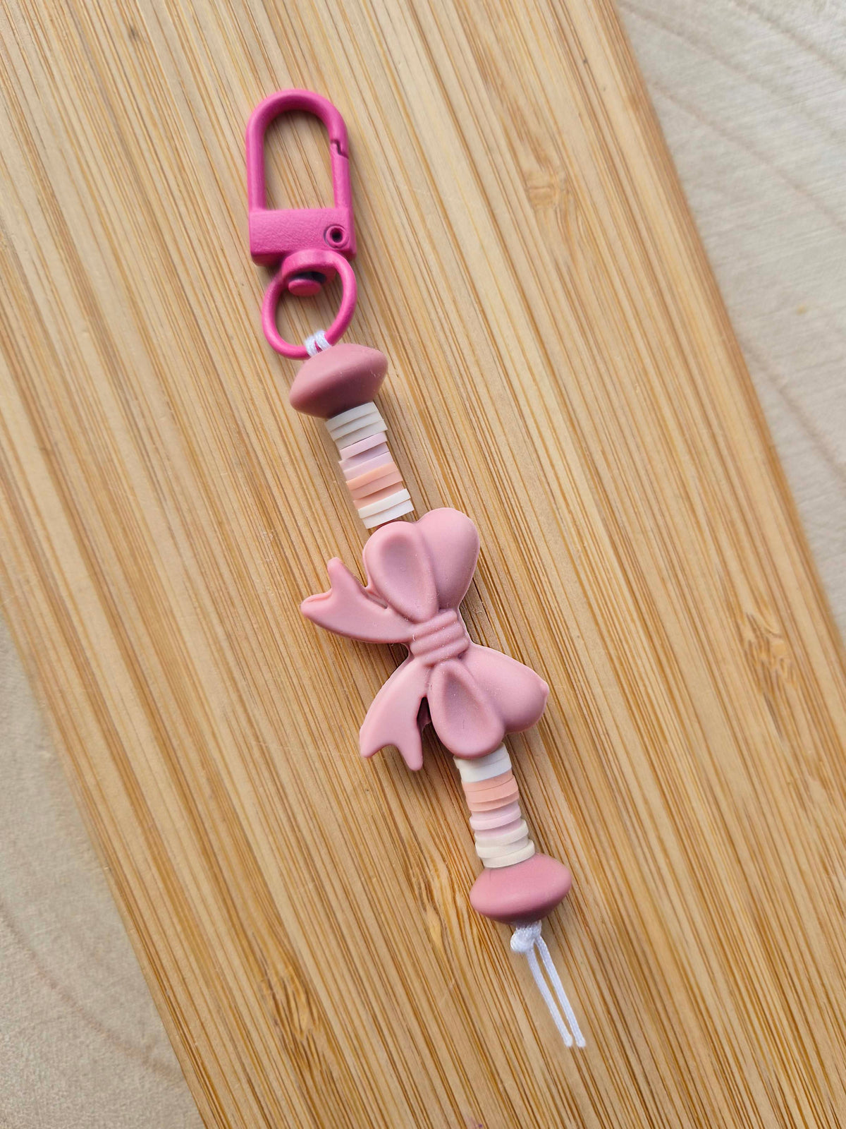 Dusty pink bow keychain on wooden board