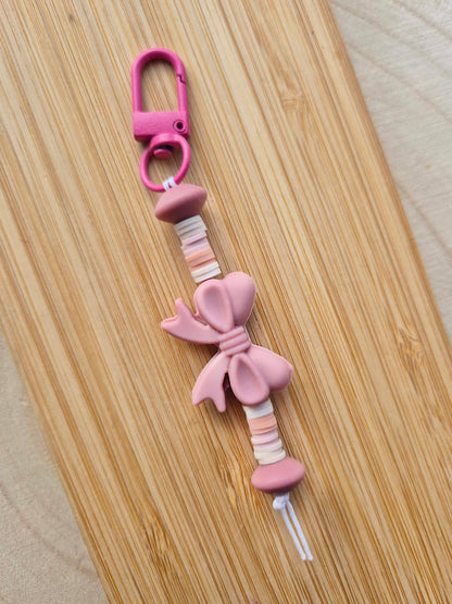 Dusty pink bow keychain on wooden board