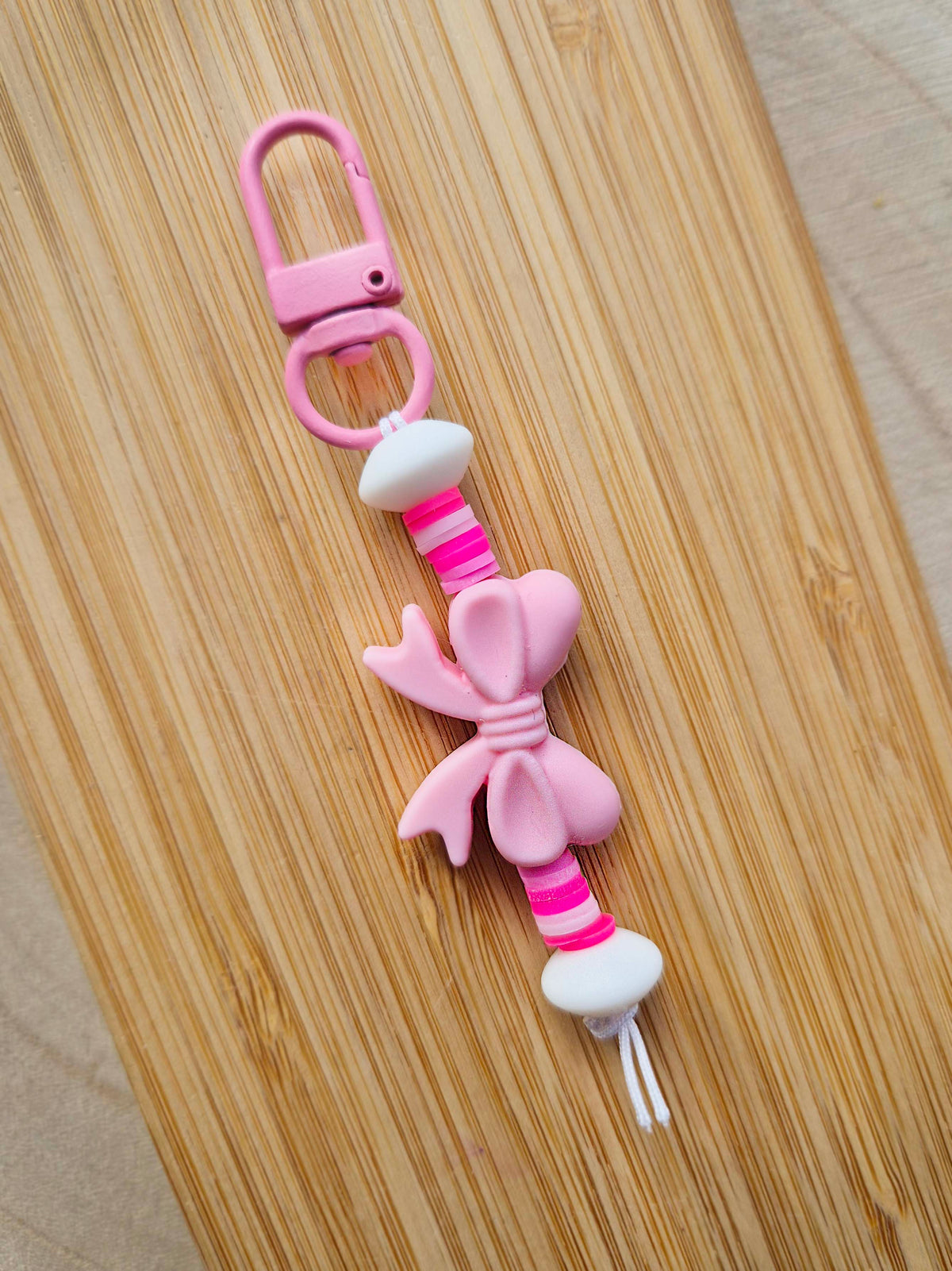 Pink bow keychain on wooden board.