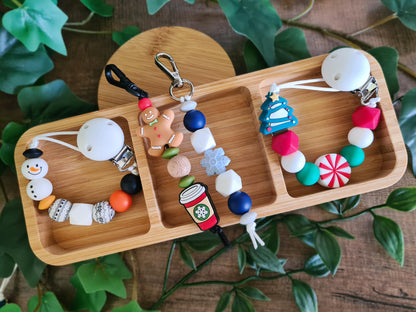 Christmas Soother Clips and keychains, zip pullers, keyrings. Get your little ones into the festive spirit with the snowman soother clip or the candy christmas tree soother clip. Treat yourself to these special Xmas keychains. Choose between the gingerbread latte or the frozen themed keyring. Made from silicone beads.
