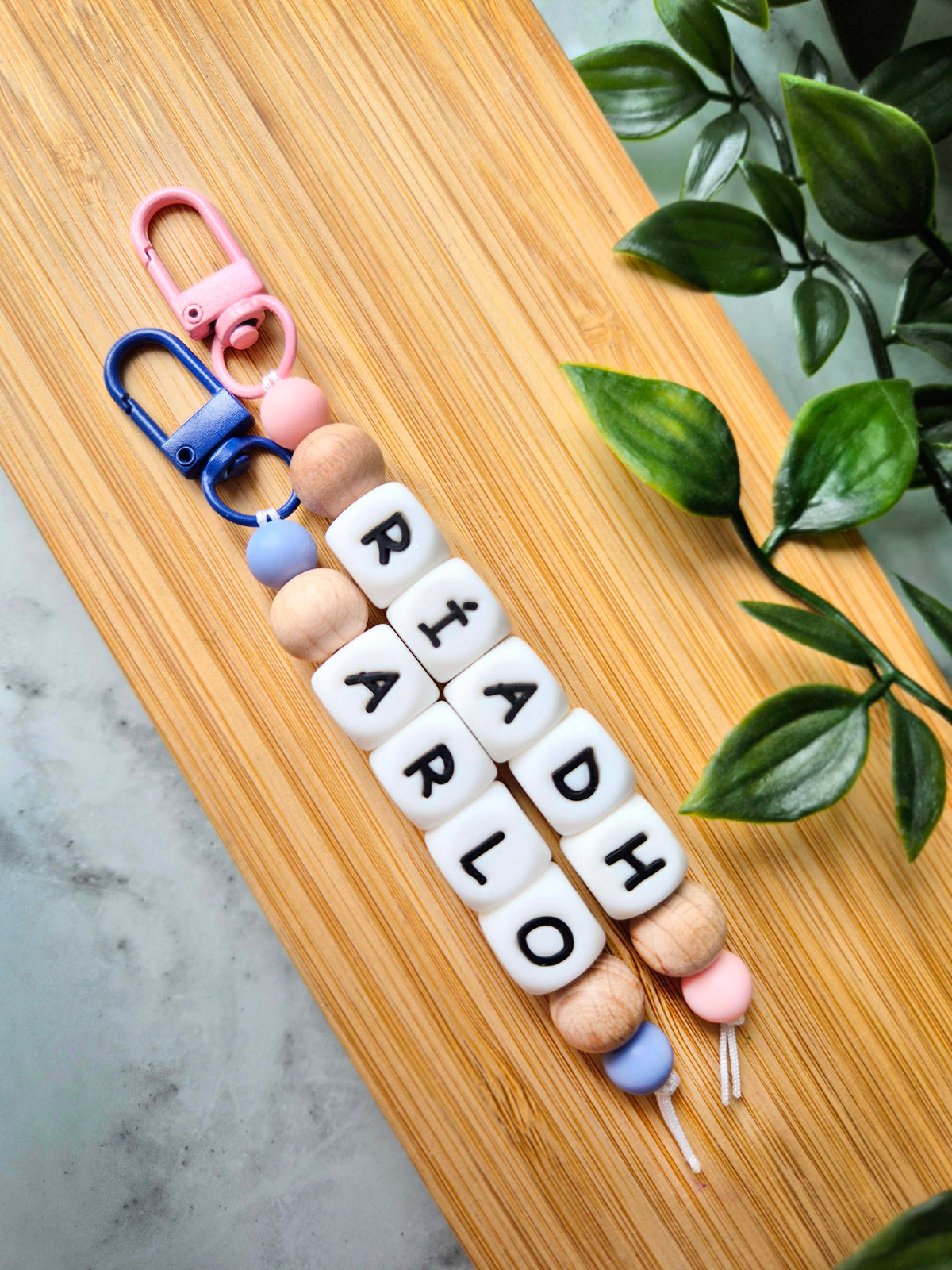 Two personalised keychains / bag charms made of white silicone letter beads and beech wood beads.