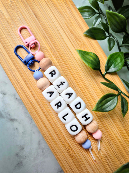 Two personalised keychains / bag charms made of white silicone letter beads and beech wood beads.