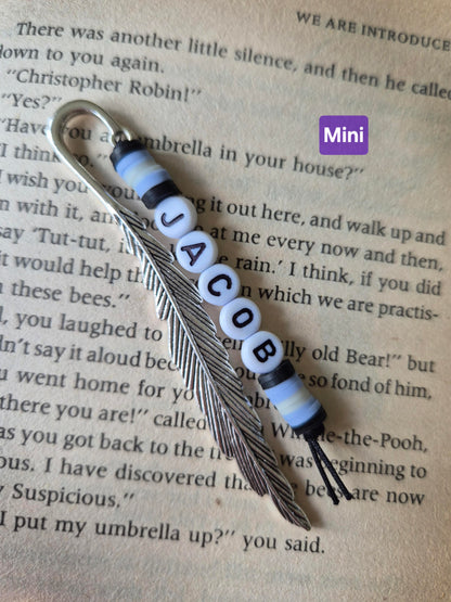 Feather bookmark with beads. Beads in blue and black and the name Jacob spelt in flat round white beads.