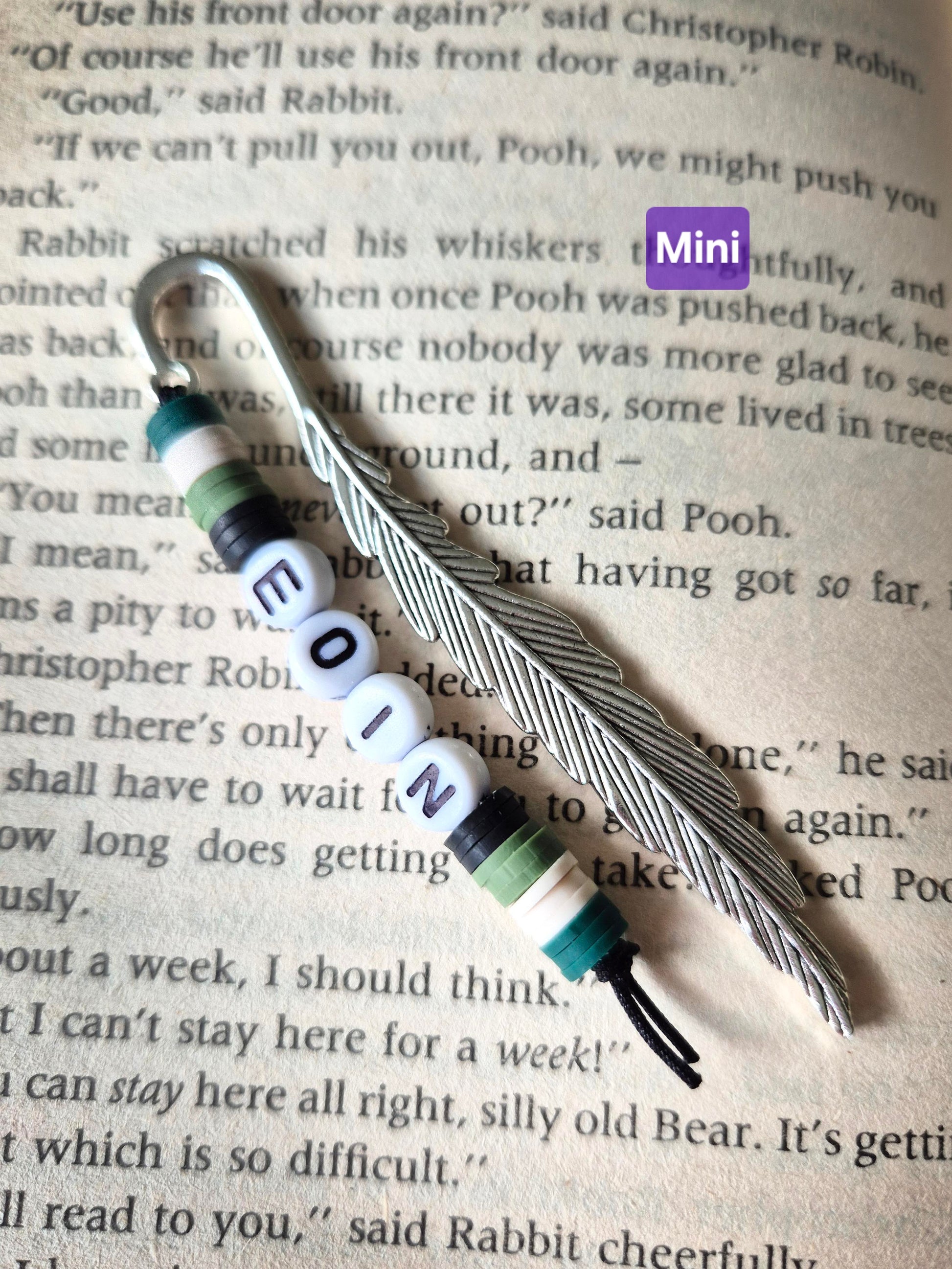 Feather bookmark with beads. Beads in green and black and the name Eoin spelt in flat round white beads.