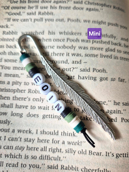Feather bookmark with beads. Beads in green and black and the name Eoin spelt in flat round white beads.